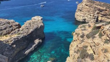 Güzel Comino deniz mağaraları ve doğal kemerler. Kristal berrak Akdeniz 'de bir tekne. Santa Marija kulesinin yakınındaki kayalıklardan görüldü. Yüksek kalite 4k görüntü