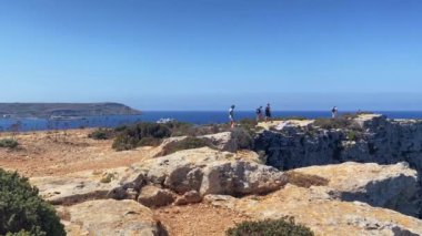 Comino, Malta -24.05.2024 - Maltese adası Comino 'daki Fener noktasını ziyaret eden turistler. Issız adanın etrafında yürüyüş yolu. Yüksek kalite 4k görüntü