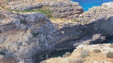 Güzel Comino deniz mağaraları ve doğal kemerler. Kristal berrak Akdeniz 'de bir tekne. Santa Marija kulesinin yakınındaki kayalıklardan görüldü. Yüksek kalite 4k görüntü