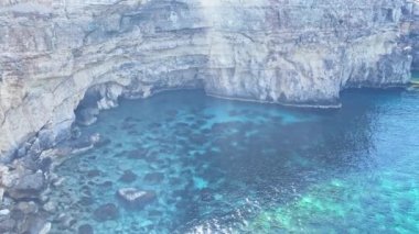 Comino, Malta 28.05.2024 - kristal berrak Akdeniz 'in şaşırtıcı güzelliği ve Santa Marija Kulesi yakınlarındaki kırmızı tur teknesi mağaralarını ziyaret ediyor. Yüksek kalite 4k görüntü