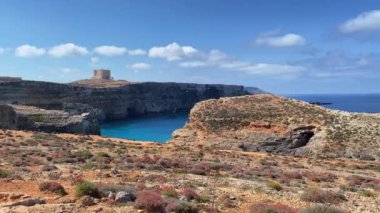 Güzel Comino deniz mağaraları ve doğal kemerler. Kristal berrak Akdeniz 'de bir tekne. Santa Marija kulesinin yakınındaki kayalıklardan görüldü. Yüksek kalite 4k görüntü