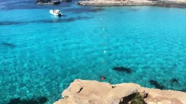 Malta 'nın Comino adasında kristal berrak turkuaz su içinde yüzen küçük bir tekne. Yüksek kalite 4k görüntü