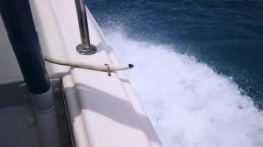 Güvertenin üstünden bir manzara, açık denizde dalgaları kıran bir yat. Yüksek kalite 4k görüntü