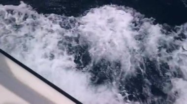Güvertenin üstünden bir manzara, açık denizde dalgaları kıran bir yat. Yüksek kalite 4k görüntü