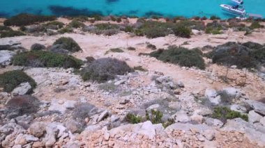 Comino, Malta 29.05.2024 - Comino adasındaki engebeli kayalık arazi, mavi lagün ve daha fazla tur teknesi ortaya çıkarıyor. Yüksek kalite 4k görüntü