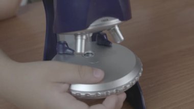 Çocuk mikroskopta ışığı açıyor. Kapatın. Yüksek kalite 4k görüntü