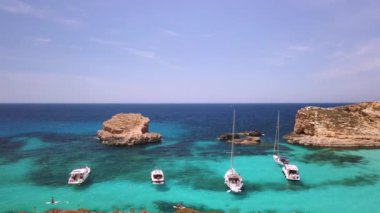 Comino, Malta 29.05.2024 - Blue lagoon yakınlarında demirlemiş botlar, yüzen ve SUP kullanan turistler. Yüksek kalite 4k görüntü