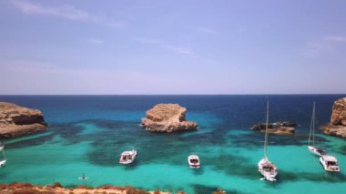 Comino, Malta 29.05.2024 - Blue lagoon yakınlarında demirlemiş botlar, yüzen ve SUP kullanan turistler. Yüksek kalite 4k görüntü