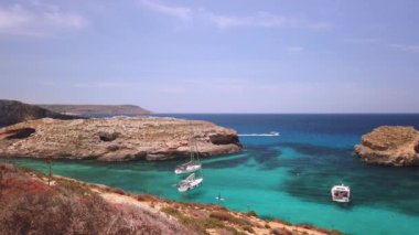 Comino, Malta 29.05.2024 - Blue Lagoon yakınlarında demirlemiş tekneler, küçük adanın etrafında yelken açarak Comino mağaralarını ziyaret ediyorlar. Yüksek kalite 4k görüntü