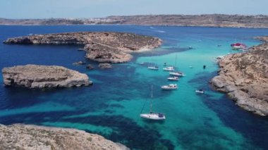 Kristal berrak turkuaz deniz suyunda yüzen tekneler. Mavi Göl, Comino, Malta Adaları. Havadan görüntü alıyoruz. Yüksek kalite 4k görüntü