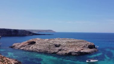 Kristal berrak turkuaz deniz suyunda yüzen tekneler. Mavi Göl, Comino, Malta Adaları. Havadan statik çekim. Yüksek kalite 4k görüntü