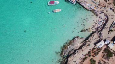 İnsanlar kristal berrak turkuaz deniz suyunda yüzüyorlar. Comino Adası, Malta, Havadan yukarıdan aşağıya doğru görüş. Yüksek kalite 4k görüntü
