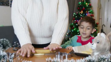 Anne ve oğlu birlikte Noel kurabiyesi yapıyorlar. Noel tatilleri ve ev hayatı. Ağır çekim. Yüksek kalite 4k görüntü
