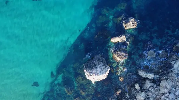 stock image Tat-Tonn or Spritzing rock, snorkeling point between Qarraba Bay and TaBabu Cove, Ghajn Tuffieha, Mgar, Malta. Aerial view of the emerald sea and rocky coast in early morning still in the shade of