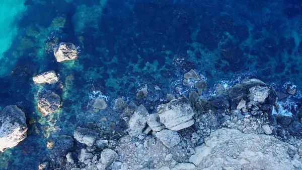 stock image Tat-Tonn or Spritzing rock, snorkeling point between Qarraba Bay and TaBabu Cove, Ghajn Tuffieha, Mgar, Malta. Aerial view of the emerald sea and rocky coast in early morning still in the shade of