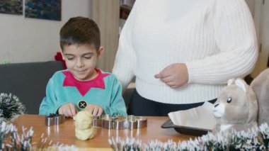 Anne ve oğlu birlikte Noel kurabiyesi yapıyorlar. Noel tatilleri ve ev hayatı. Ağır çekim. Yüksek kalite 4k görüntü