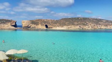 Comino, Malta 28.05.2024 - Malta 'nın Comino Adası' ndaki kristal berrak turkuaz su gölünde yüzen turistler. Yüksek kalite 4k görüntü