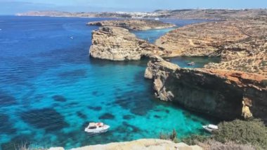 Güzel Comino deniz mağaraları ve doğal kemerler. Kristal berrak Akdeniz 'de bir tekne. Santa Marija kulesinin yakınındaki kayalıklardan görüldü. Yüksek kalite 4k görüntü