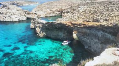 Güzel Comino deniz mağaraları ve doğal kemerler. Kristal berrak Akdeniz 'de bir tekne. Santa Marija kulesinin yakınındaki kayalıklardan görüldü. Yüksek kalite 4k görüntü