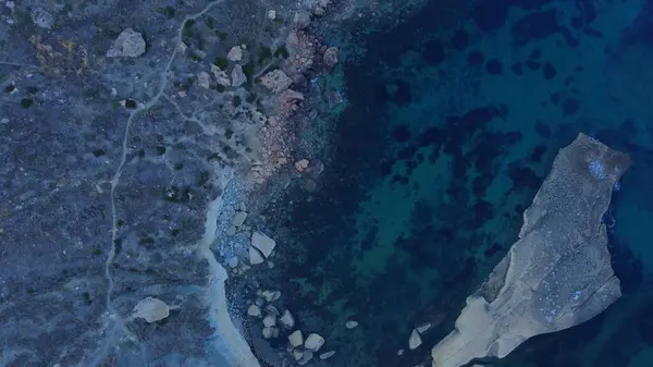 stock image Tat-Tonn or Spritzing rock, snorkeling point between Qarraba Bay and TaBabu Cove, Ghajn Tuffieha, Mgar, Malta. Aerial view of the emerald sea and rocky coast in early morning still in the shade of