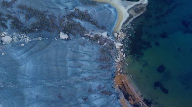 Tat-Tonn ya da Spritzing kayası, Qarraba Körfezi ile TaBabu Koyu, Ghajn Tuffieha, Mgar, Malta arasında şnorkelle yüzme noktası. Sabahın erken saatlerinde zümrüt deniz ve kayalık kıyı manzarası hâlâ gölgede.