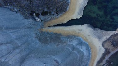 Tat-Tonn or Spritzing rock, snorkeling point between Qarraba Bay and TaBabu Cove, Ghajn Tuffieha, Mgar, Malta. Aerial view of the emerald sea and rocky coast in early morning still in the shade of clipart