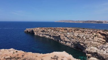 Cominotto, Malta, Comino yakınlarındaki ıssız adanın deniz mağaralarının havadan görünüşü. Çerçevede uçan martı. Yüksek kalite fotoğraf