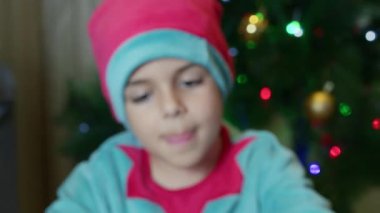 Başparmak yukarı. Noel ağacının önünde elf kostümü giymiş genç bir çocuğun portresi. - Evet. Yüksek kalite 4k görüntü