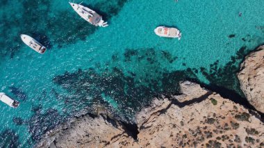 Kristal berrak turkuaz deniz suyunda yüzen tekneler. İnsanlar yüzüyor. Mavi Göl, Comino, Malta Adaları. Havadan yüksek açı görüntüsü. Yüksek kalite fotoğraf