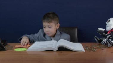 Çocuk finans okuyor, üzgün hisler besliyor. İskelet para bankası ve paralar masanın üstünde. Yüksek kalite 4k görüntü