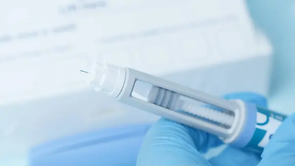 Diyabetik ilaç kaleminin iğnesini kapat. Mavi parlayan kalemli eller. Yüksek kalite fotoğraf