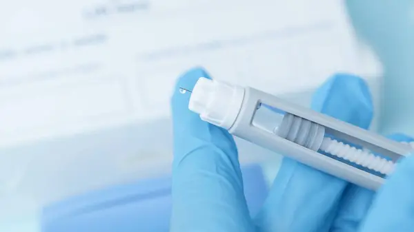 Diyabetik ilaç kaleminin iğnesini kapat. Mavi parlayan kalemli eller. Yüksek kalite fotoğraf