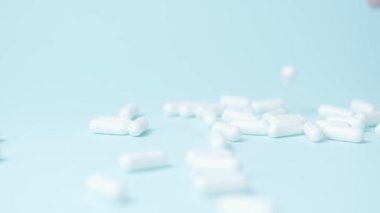 Kadın El, beyaz kapsülleri yerleştiriyor. Mavi arka plana izole edilmiş haplar. Tıbbi sorunlar, ağrı kesiciler veya bağımlılık konsepti. Dikkatini topla. Yüksek kalite 4k görüntü