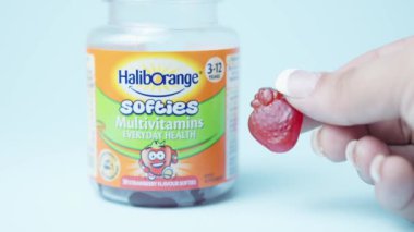 Qawra, Malta, 26.10.2024 - Çocuklar için Cheving vitamini tutan kadın eli, çilekli vitamin yumuşakları. Yüksek kalite 4k görüntü