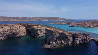 Cominotto, Malta, Comino yakınlarındaki ıssız adanın deniz mağaralarının havadan görünüşü. Çerçevede uçan martı. Yüksek kalite fotoğraf