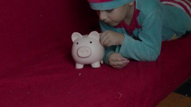 Domuz kumbarasıyla oynayan elf gibi giyinmiş şirin bir çocuk. Yüksek kalite 4k görüntü