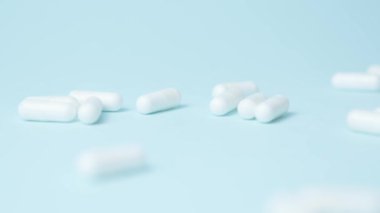 Bir sürü beyaz kapsül, mavi arka planda izole edilmiş haplar. Tıbbi sorunlar, ağrı kesiciler veya bağımlılık konsepti. Dikkatini topla. Yüksek kalite 4k görüntü