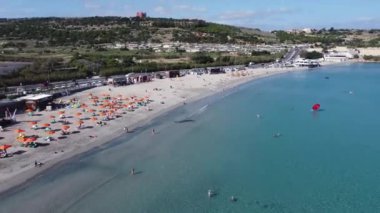 Mellieha, Malta 18.11.2024 - Malta Havalimanı, Kasım ayında şemsiyeli beyaz kum plajı. Geri geri uçmak, turkuaz deniz suyunu ortaya çıkarmak. Yüksek kalite 4k görüntü
