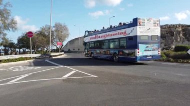 Salini, Malta 22.11.2024 Saini tatil köyünün önündeki kavşağın yakınında trafik var. Buradan geçen bir gezi otobüsü. Yüksek kalite 4k görüntü