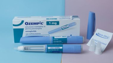 Qawra, Malta - 01.11.2024 - Mavi ve pembe arka planda iki enjektör kalem, iğne ve alkol mendilli Ozempic 1mg ambalajı. Yüksek kalite fotoğraf