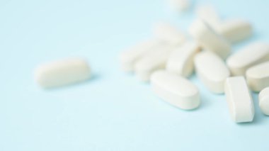 Açık mavi arka planda beyaz haplar, hafif odaklanma, makro raf odaklama. Yüksek kalite 4k görüntü