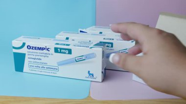 Qawra, Malta, 26.10.2024 - Ozempic semaglutit enjeksiyon kalemleriyle dolu kutular. Kadın eli ilaçla birlikte kutuyu alıyor. Yüksek kalite 4k görüntü