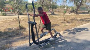 Sevimli çocuk, dışarıda spor salonunda, makinede egzoz çıkarıyor. Yüksek kalite 4k görüntü