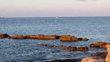 Günbatımı Cirkewwa Malta 'da dalgalar denizde kayaların üzerinde süzülüyor. Yüksek kalite 4k görüntü