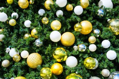 Altın, gümüş ve beyaz mücevherlerle süslenmiş bir Noel ağacının yakınında. 