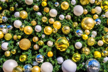 Altın, gümüş ve beyaz mücevherlerle süslenmiş bir Noel ağacının yakınında. 