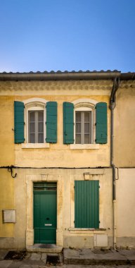 Arles, Fransa, 9 Eylül 2023, Emile Barrere caddesinde yeşil panjurlu sarı bir duvar manzaralı ev.