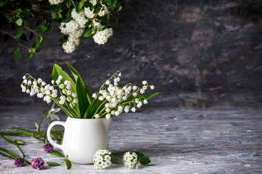 Buket baharı vadideki beyaz zambak. Kırsal tarzda gri ahşap masa üzerinde çiçekli bir hayat. Çiçek açan dallar, çiçek açan bahçeler..