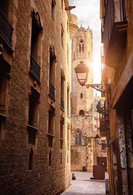 Gothic Quarter in Barcelona, Catalonia, Spain. Vew at ancient tower. Antique lamps on the narrow streets with medieval buildings. Architecture of old town stone houses. Evening sky and street lanterns