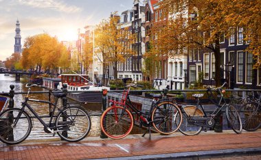 Amsterdam kanalı üzerinde bisiklet, sonbahar sarı yaprak düşüşü. Hollanda 'da Amstel Nehri manzaralı pitoresk kasaba manzarası